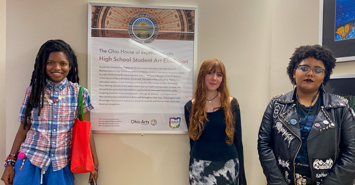 students standing next to art work